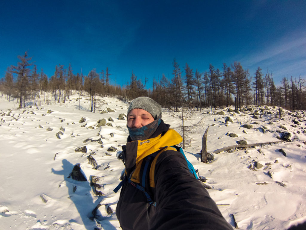 Алексей Забелин на фоне заснеженных камней на склоне Большого Саранакана